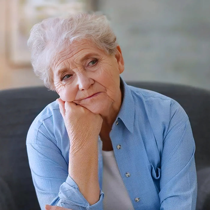 Depressed elderly woman sitting in arm-char at home