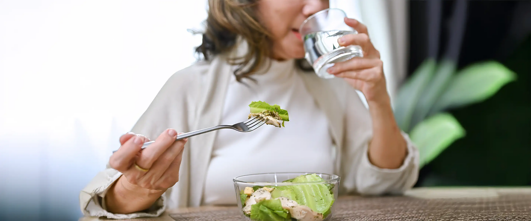 Healthy and happy Asian-aged eating salad bowl and drinking water 