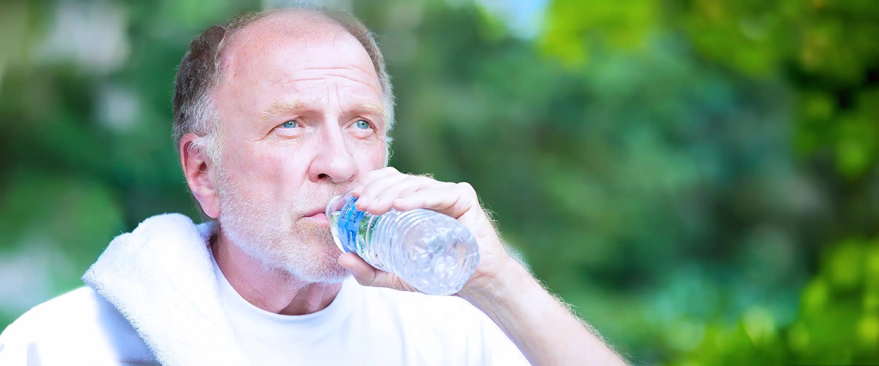 Thirsty senior mature man drinking water outside