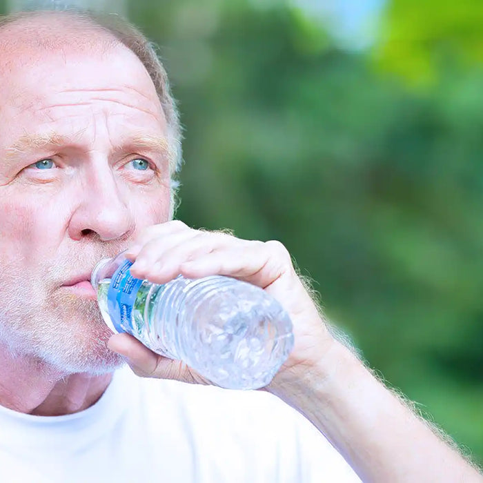 Thirsty senior mature man drinking water outside