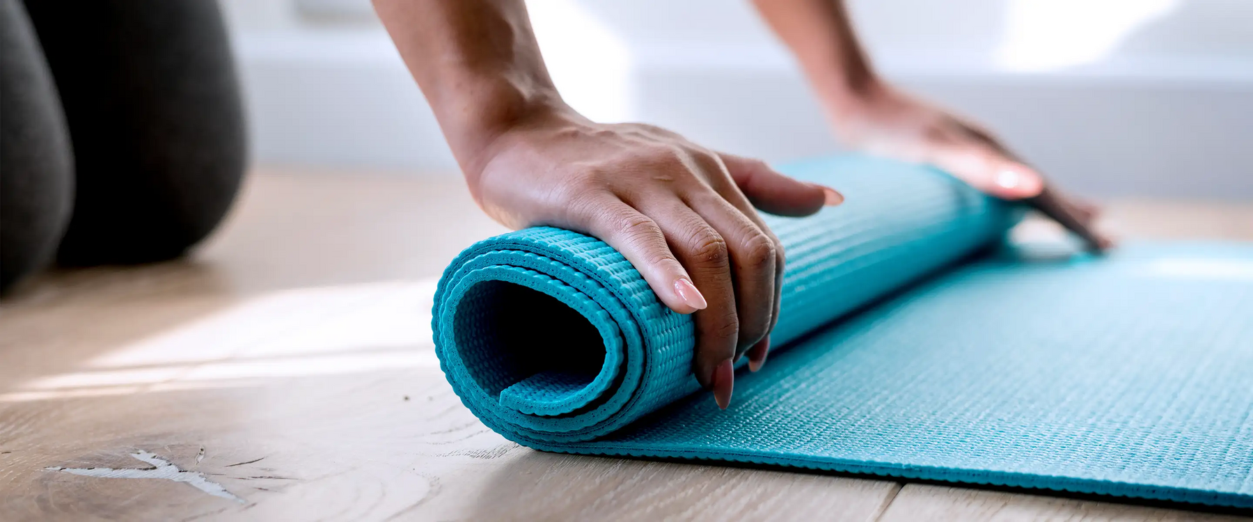 Woman rolling yoga mat on the floor