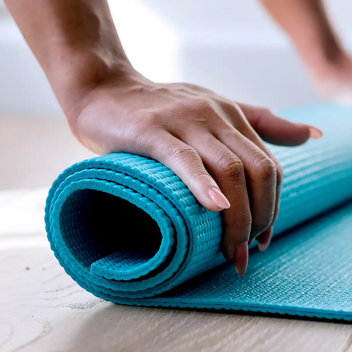 Woman rolling yoga mat on the floor