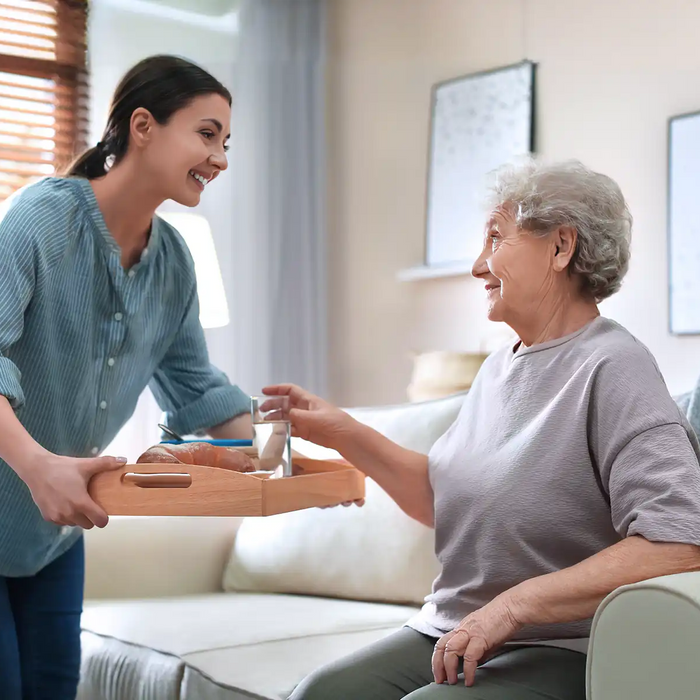 Young woman serving dinner for elderly woman